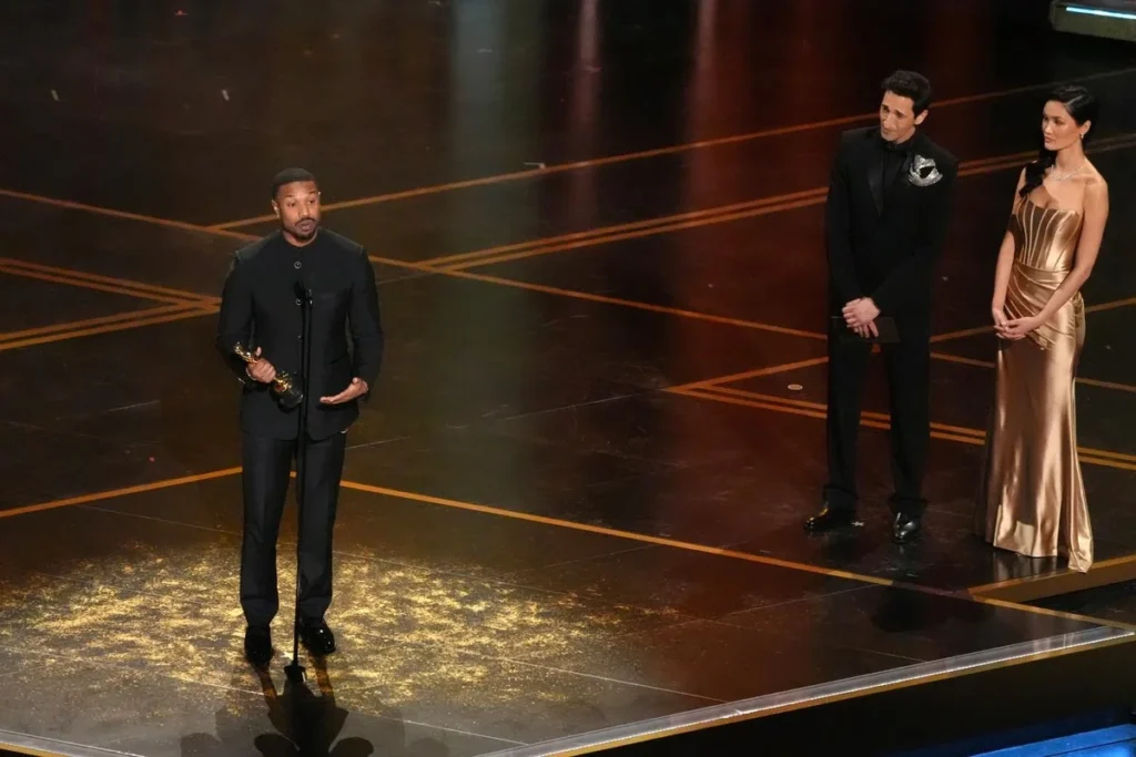 Michael B. Jordan neemt de Oscar voor beste acteur in een hoofdrol voor "Sinners" in ontvangst tijdens de Oscaruitreiking op zondag 15 maart 2026 in het Dolby Theatre in Los Angeles. Adrien Brody kijkt toe vanaf rechts.